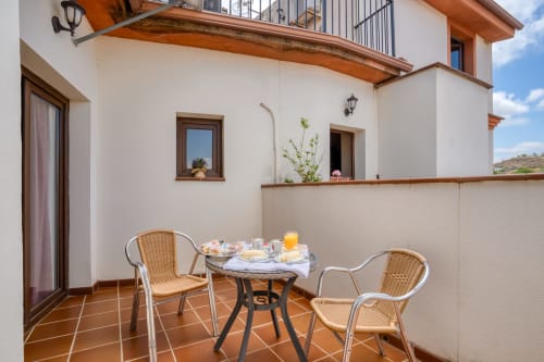 Petit-déjeuner en terrasse ensoleillée à l'Hôtel Balcón De Los Montés avec fauteuils en rotin, vue montagne et paysage de Colmenar
