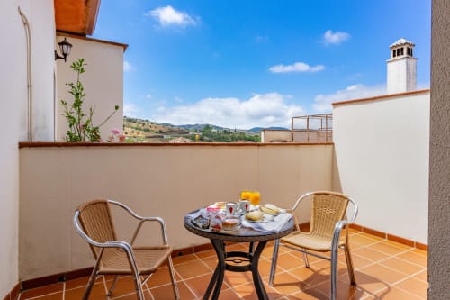 Terrasse de la suite Hotel Balcón De Los Montés à Colmenar avec vue sur les montagnes, table à manger et chaises en rotin