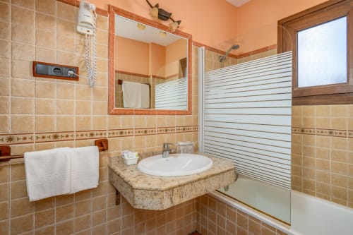 Salle de bain avec carrelage beige, comptoir en granit et douche à l'italienne à l'Hôtel Balcón De Los Montés