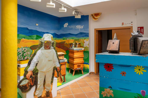 Exposition du Museo de la Miel à Colmenar avec apiculteur et modèles de ruches colorées