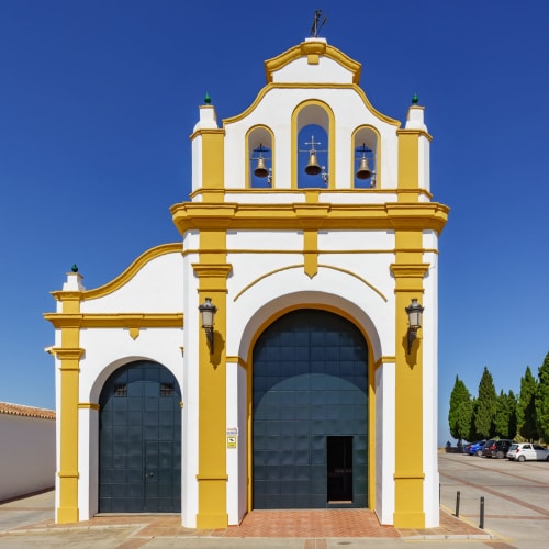 Église coloniale jaune vif et blanche avec clocher à Colmenar, Espagne