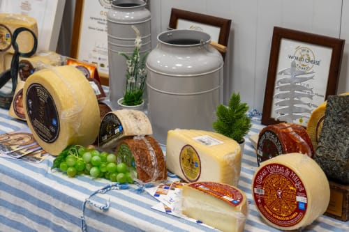 Élégante présentation de fromages affinés à l'Hôtel Balcón De Los Montés avec meules emballées, raisins frais et pain de Colmenar
