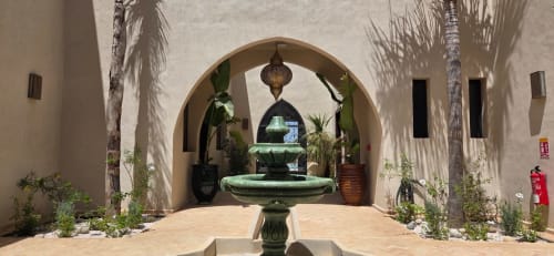 Cour du Riad Arkaya à Essaouira avec colonnade en arc, fontaine, palmiers et lanterne marocaine