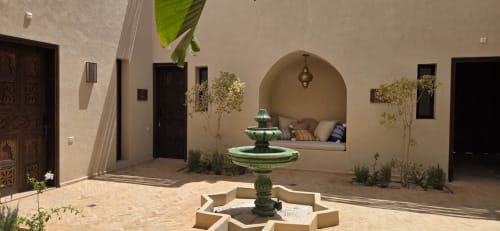 Cour du Riad Arkaya à Essaouira avec alcôve voûtée traditionnelle, fontaine centrale et plantes luxuriantes.