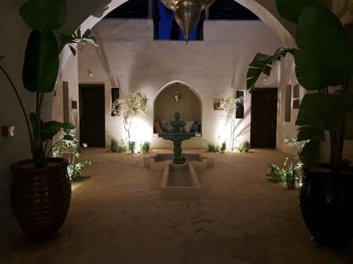 Cour du Riad Arkaya à Essaouira la nuit : lanterne, fontaine, murs blancs et plantes en pot