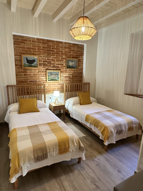 Habitación doble en El Escondite De Pedro Malillo, Candeleda, con detalles mostaza y pared de ladrillo visto