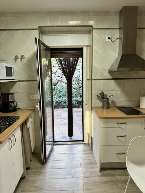 Cocina moderna en El Escondite De Pedro Malillo con muebles crema, encimeras de madera y puertas francesas hacia el patio jardín