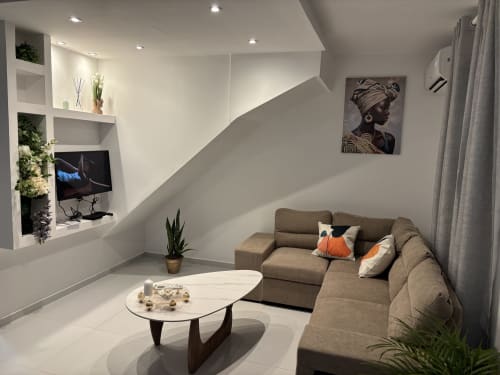 Modern cottage living room at Domaine De Marly with beige sofa, white marble table, built-in shelving, and garden view in