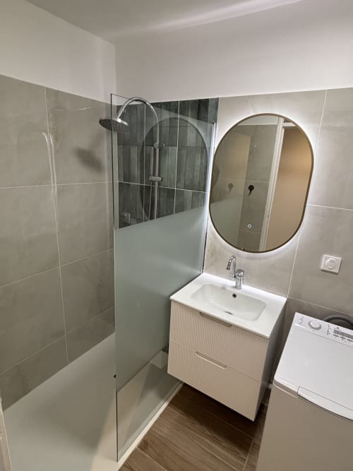 Modern bathroom with walk-in shower, vanity sink, and illuminated oval mirror at Domaine De Marly cottage, Sainte-Anne