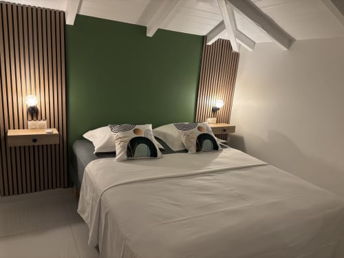 Modern bedroom in Gîte Cythère cottage at Domaine De Marly, Sainte-Anne with green accent wall and white linens