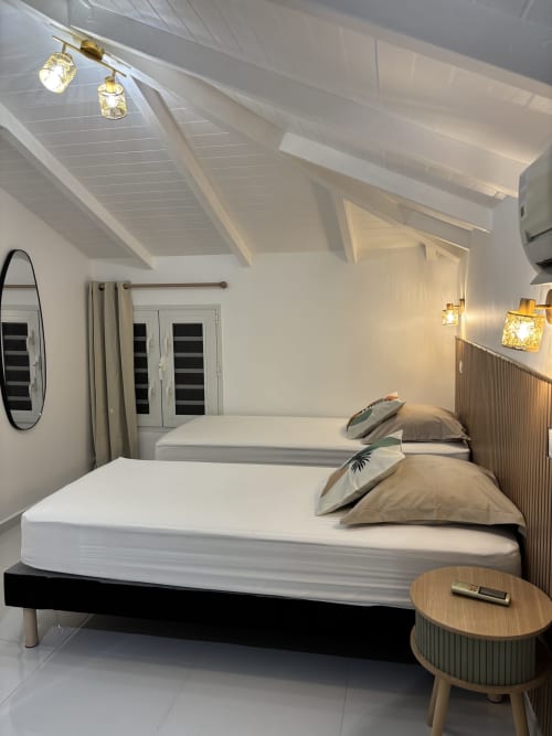 Modern bedroom in Gîte Cythère cottage at Domaine De Marly, Sainte-Anne with twin beds, sloped ceiling, and ambient lighting