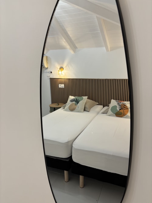 Mirror reflection of modern bedroom in Gîte Cythère cottage at Domaine De Marly, Sainte-Anne, featuring twin beds with
