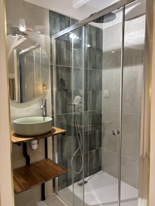 Modern bathroom at Domaine De Marly cottage in Sainte-Anne with round sink, rainfall showerhead, and dark tile shower