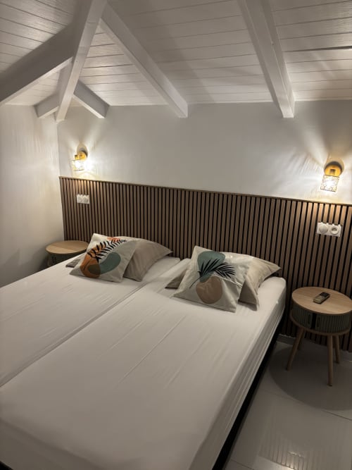 Modern bedroom in Gîte Cythère cottage at Domaine De Marly, Sainte-Anne with white beams, garden view, and contemporary