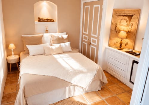 Chambre élégante au Mas d'Olivier avec linge crème, carrelage en terre cuite, niche blanche et vue sur le jardin en Provence.