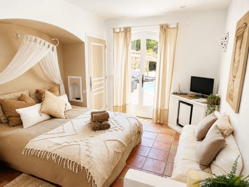 Chambre élégante au Mas d'Olivier avec lit à baldaquin, salon et vue sur la piscine à la Côte d'Azur