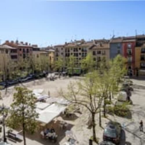 Patio del apartamento Placeta en Vic, España con edificios coloridos, árboles verdes y vistas de la ciudad