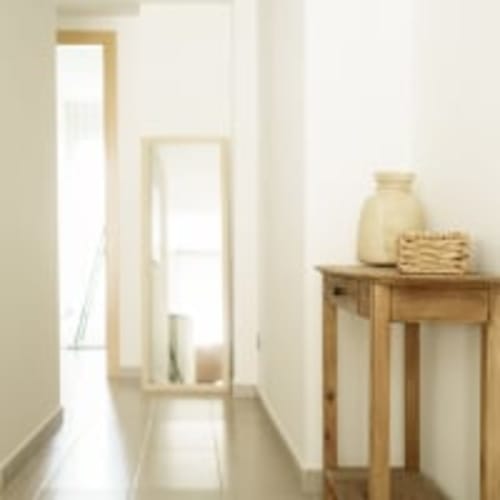 Pasillo minimalista del hotel Racons en Vic con muebles de madera, espejo y luz natural de las ventanas
