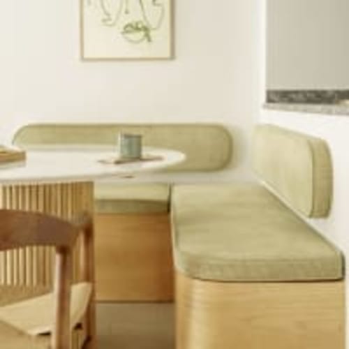 Comedor moderno en el apartamento Racons de Vic con asientos color crema, mesa redonda y muebles de madera