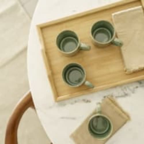 Cuatro tazas de cerámica verde colocadas en una bandeja de madera en el apartamento Racons de Vic, España