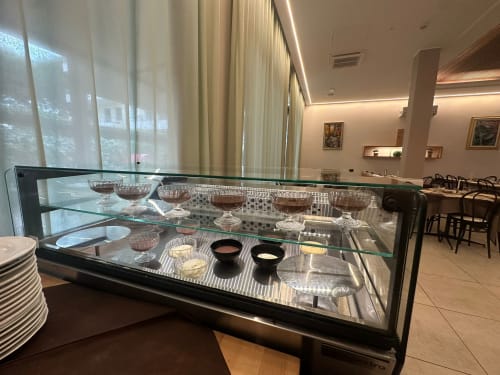 Glass display case with crystal bowls and tableware in Hotel Verdi's dining area, Jesolo