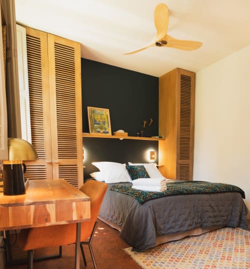 Chambre moderne aux Jardins de Majorelle à Avignon avec mobilier en bois, mur d'accent noir et ventilateur de plafond