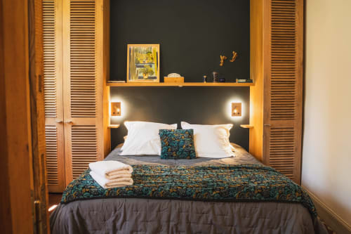 Chambre accueillante aux Jardins de Baracane avec parure motifs, oreillers blancs et accents bois chaleureux à Avignon