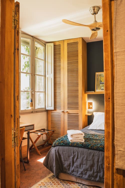 Chambre chaleureuse aux boiseries aux Jardins de Baracane à Avignon, vue sur le jardin, ventilateur de plafond et mobilier traditionnel