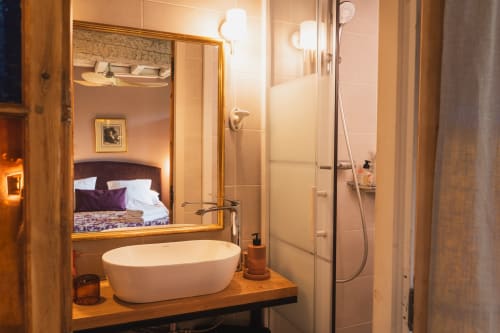 Salle de bains moderne aux Jardins de Monet à Avignon avec lavabo ovale blanc, miroir, douche et vue sur la chambre