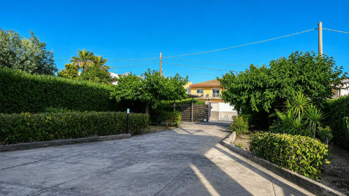 Cancellata d'ingresso alla Villa Leuka San Lorenzo a Noto, con siepi verdeggianti e la villa mediterranea sullo sfondo