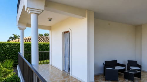Balcone di Villa Leuka a Noto con vista sul giardino, colonne bianche, sedute nere e paesaggio rurale