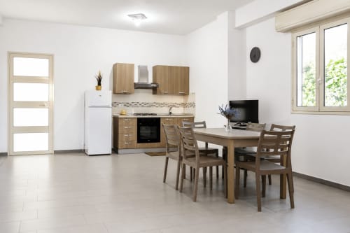 Cucina e zona living moderna di Villa Leuka San Lorenzo, Noto con tavolo in legno, sedie e cucina attrezzata