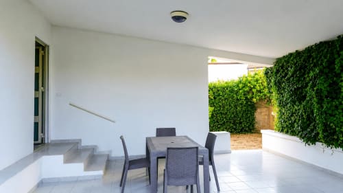 Terrazza coperta con tavolo da pranzo, sedie e muri ricoperti di edera a Villa Leuka a Noto, Sicilia
