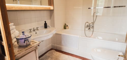 Salle de bains luxueuse aux Jardins de Baracane à Avignon avec vasque blanche arrondie, baignoire et décor en porcelaine bleu classique