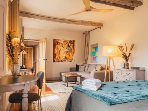 Chambre spacieuse aux poutres apparentes aux Jardins de Baracane à Avignon, vue sur jardin, canapé et équipements modernes