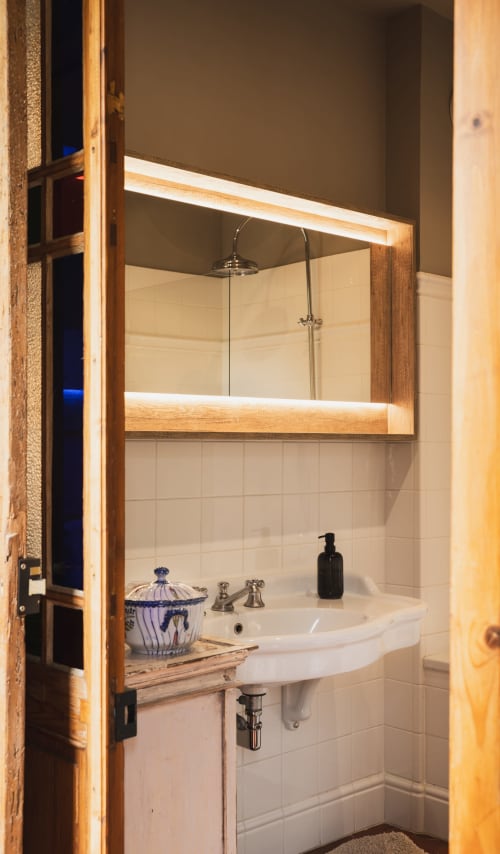 Miroir de salle de bains moderne avec éclairage chaleureux à l'hôtel-boutique Les Jardins de Baracane à Avignon