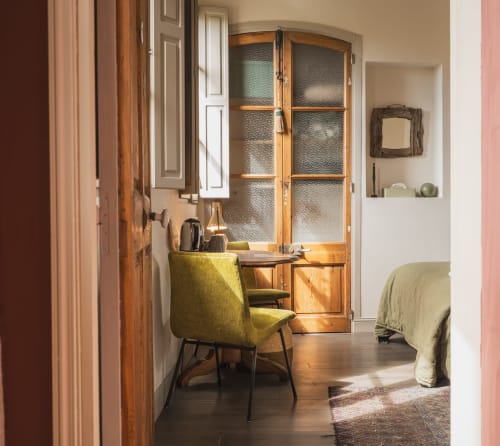 Chambre Les Jardins d'Eden aux Jardins de Baracane à Avignon avec fauteuil vintage, meuble en bois et vue sur le jardin