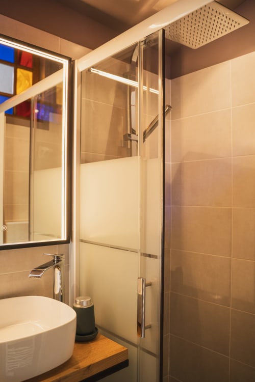 Salle de bain moderne avec douche pluie, vasque suspendue et miroir lumineux à l'hôtel-boutique Les Jardins de Baracane à Avignon