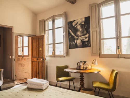 Chambre élégante aux Jardins de Baracane à Avignon avec fauteuils verts vintage, bureau en bois et vue sur jardin