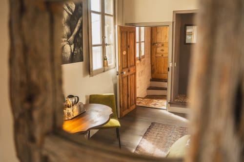 Couloir accueillant de la chambre aux Jardins de Baracane à Avignon avec portes en bois, fauteuil vert et lumière naturelle