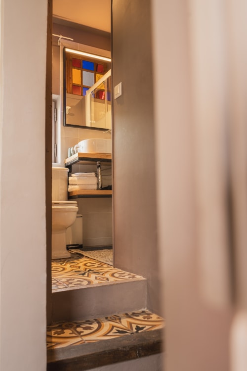 Salle de bain moderne aux carrelages colorés et miroir en verre dépoli, hôtel boutique Les Jardins de Baracane à Avignon