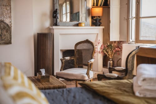 Chambre élégante aux Jardins de Baracane à Avignon avec cheminée, fauteuil cannelé et vue sur le jardin