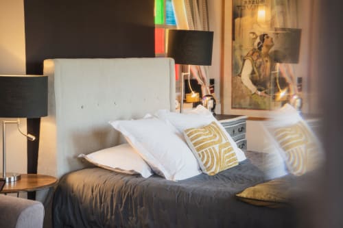 Chambre moderne aux Jardins de Baracane à Avignon avec tête de lit blanche, coussins dorés et vue sur le jardin