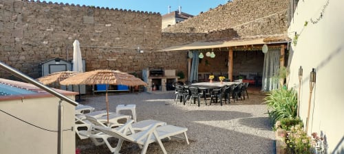 Patio de Cal Belló con tumbonas, muros de piedra, zona de comedor y sombrillas en Hostafrancs, Lleida