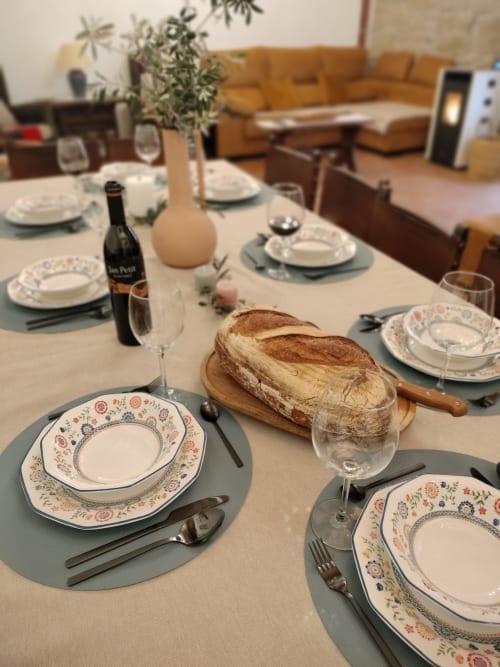 Mesa de comedor elegante en el hotel Cal Belló de Lleida con servicio de platos, pan, vino y centro de mesa de verduras