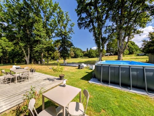 Vaste jardin de La Clairière aux Chênes avec piscine, terrasse, tables de repas et chênes centenaires.