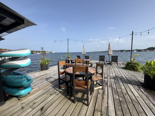 Waterfront deck at BarrBra BnB in Bocas del Toro with dining tables, kayaks, and umbrellas overlooking the Caribbean Sea