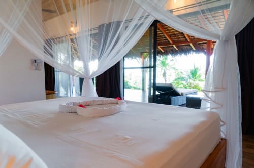 Chambre de villa bord de mer luxe au Belamandy Lodge, Nosy Be avec lit à baldaquin, terrasse vue mer et jardins tropicaux