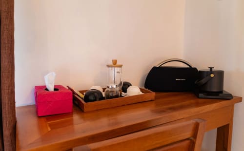 Bureau d'accueil de l'hôtel Belamandy Lodge avec boîte de mouchoirs, plateau en bois, mixeur et enceinte Hamilton Beach
