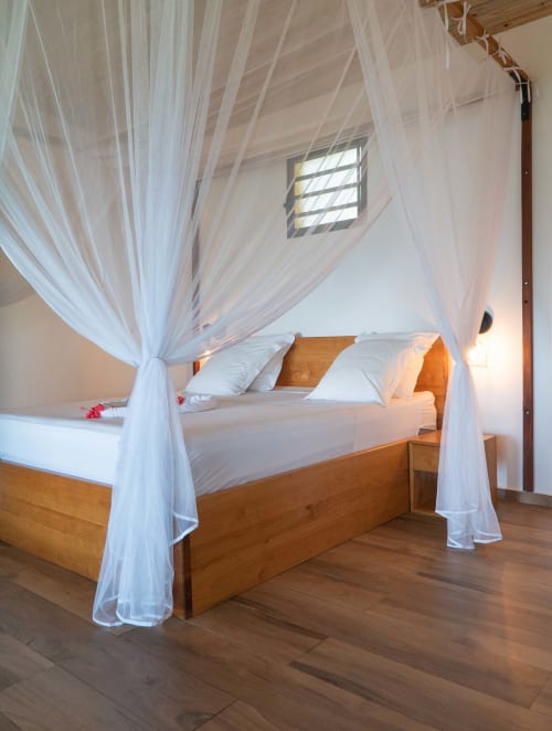 Lit à baldaquin élégant avec voilages blancs diaphanes à la villa Belamandy Lodge à Nosy Be, Madagascar
